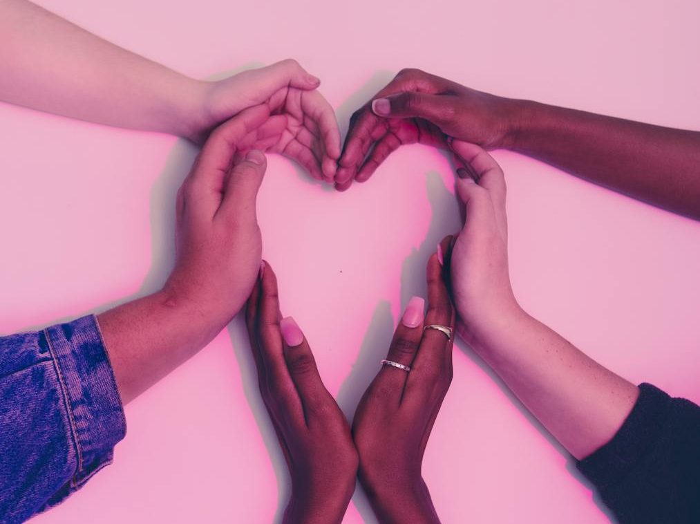 human hands forming heart on white surface
